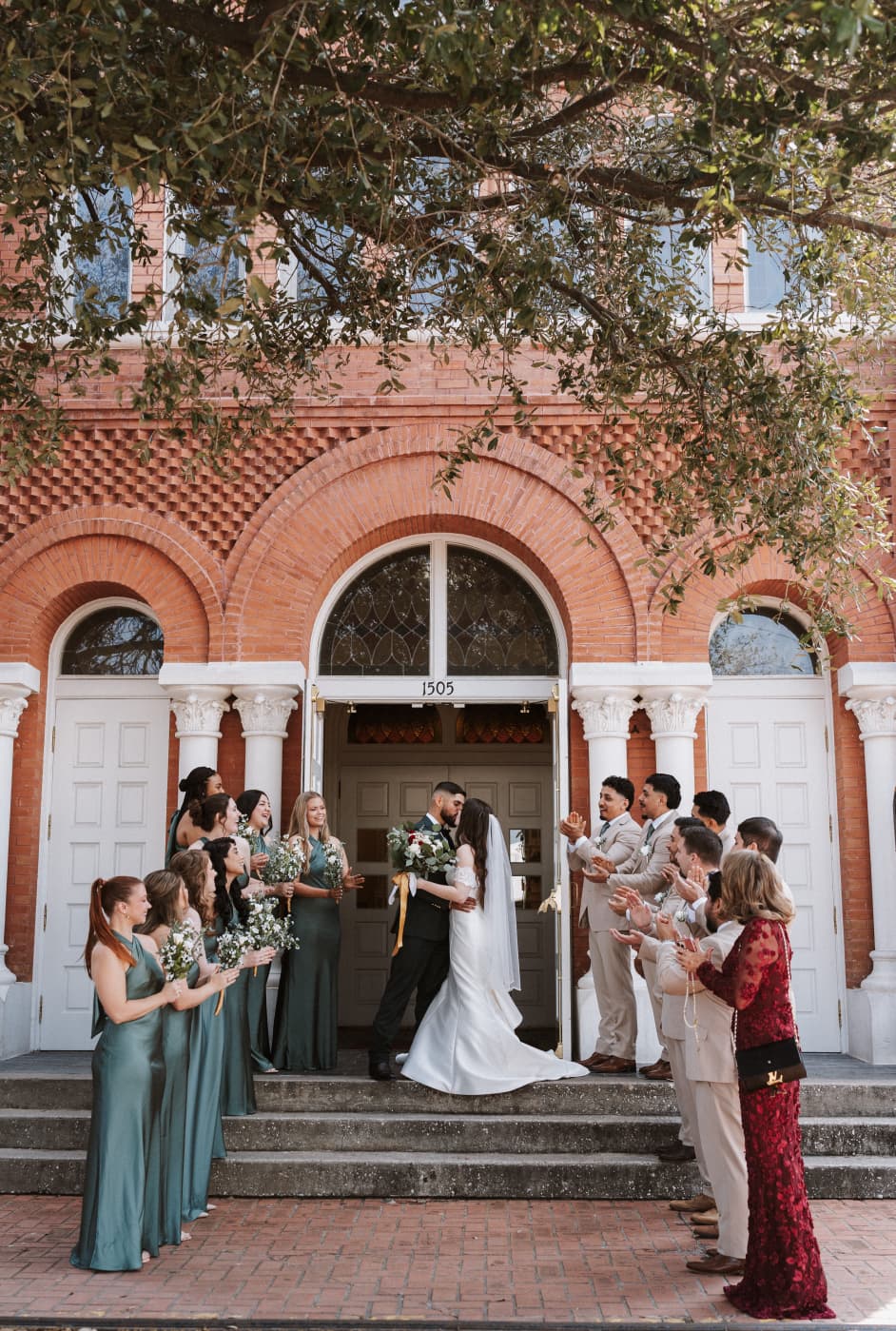 Newlyweds kissing as the wedding party cheers