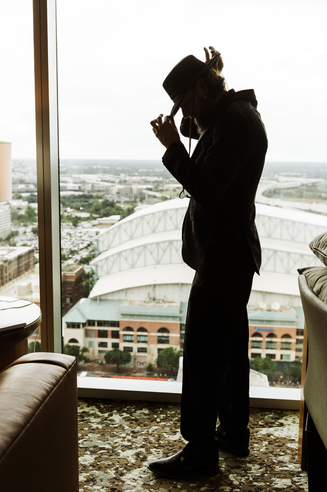 Groom adjusting his hat by the window