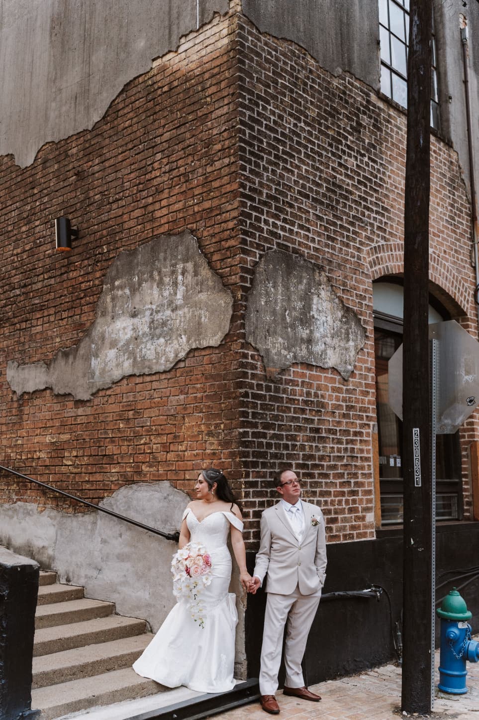 Bride and groom by a brick building downtown