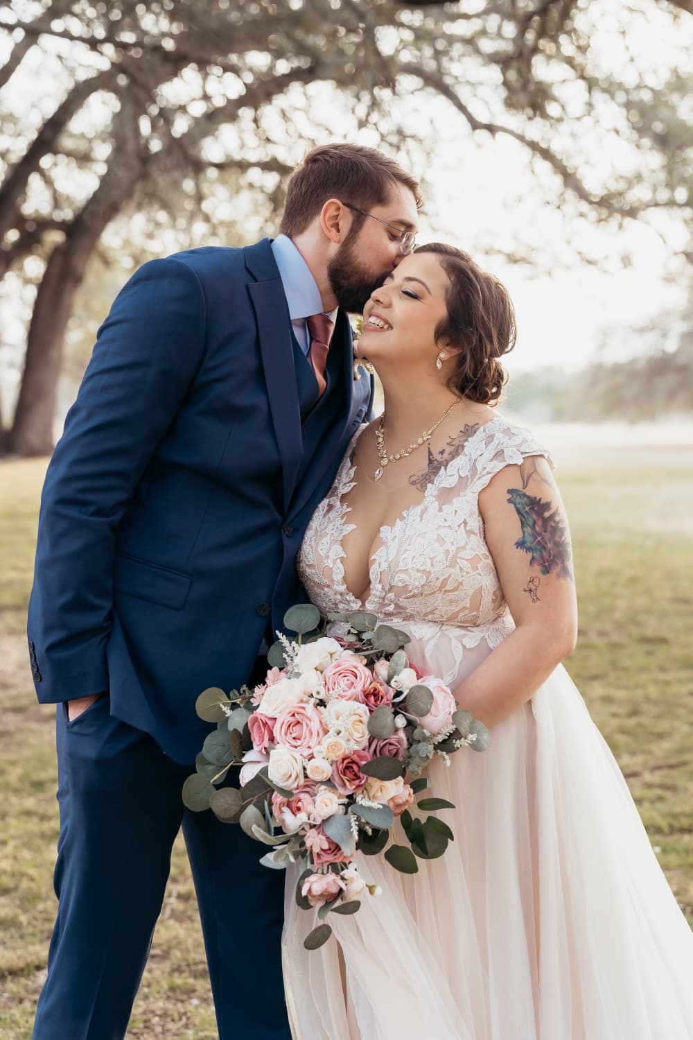 Groom kissing his bride under the oaks